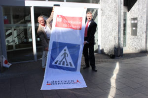 Klaus Ziele (links) vom Lübecker Marathon e.V. bekommt vom Vorstand der Sparkasse zu Lübeck, Frank Schumacher, die neuen Hinweisfahnen. Quelle: PRO EVENT